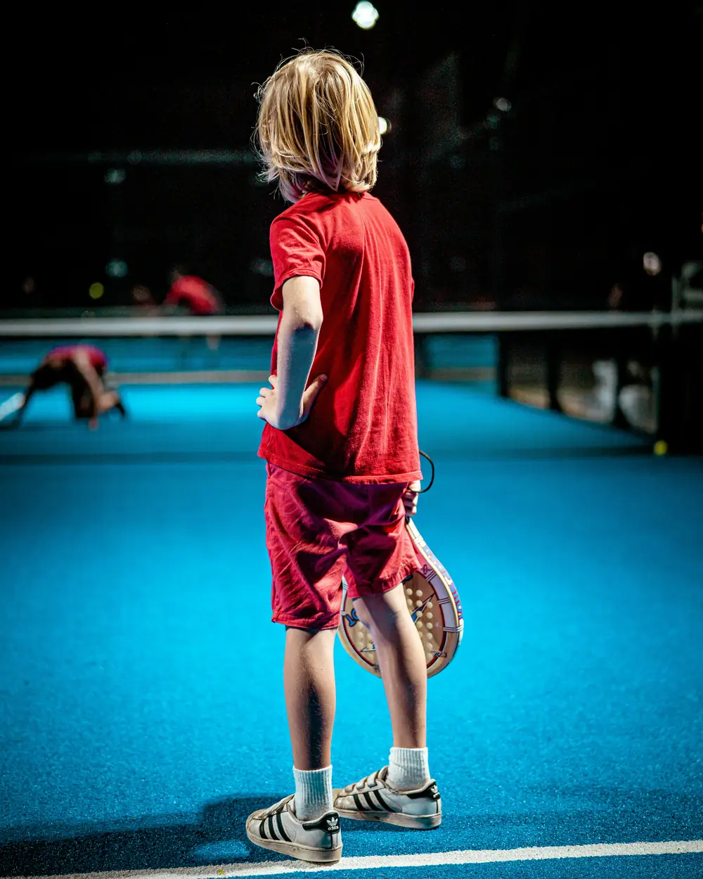 A young player with a padel racket waiting on court